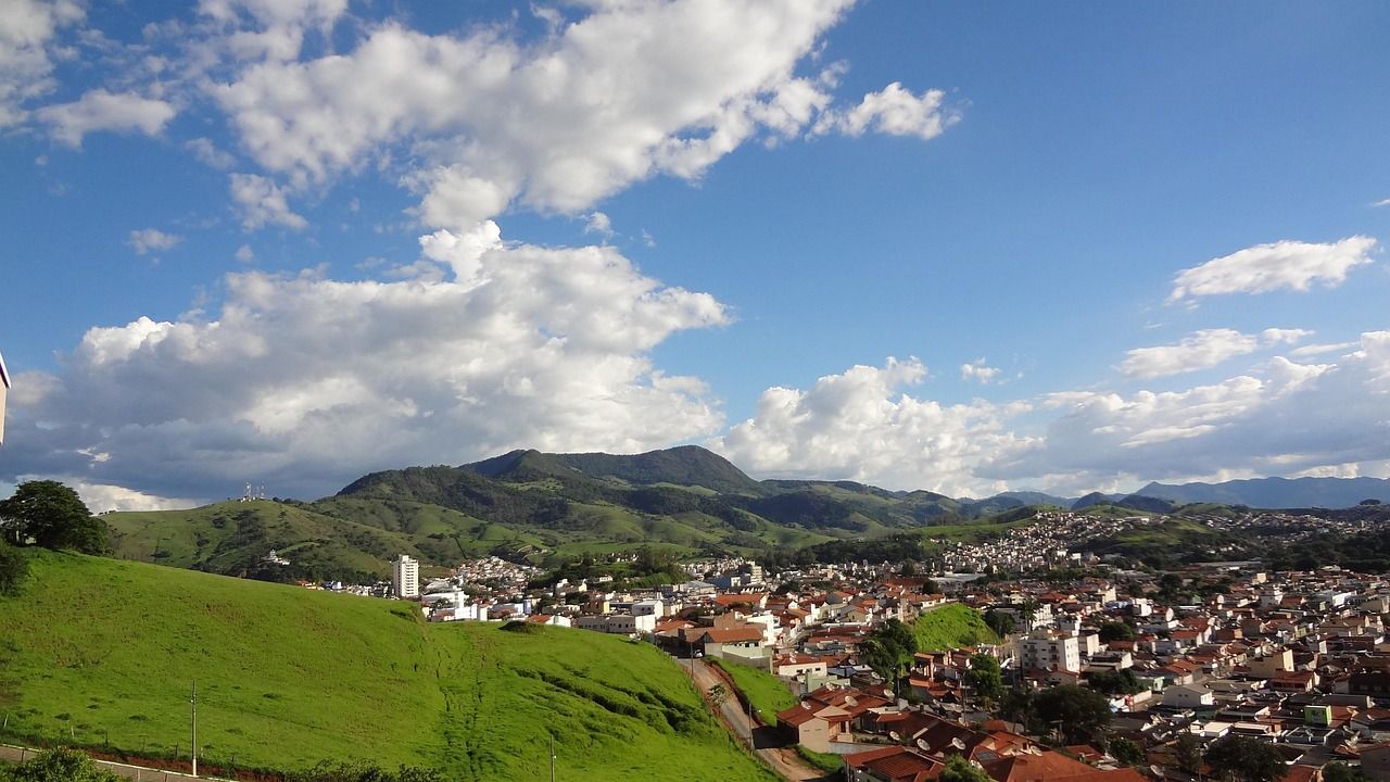 Cidade pequena num vale, com casas de telhado de barro, morros verdes e a serra ao fundo