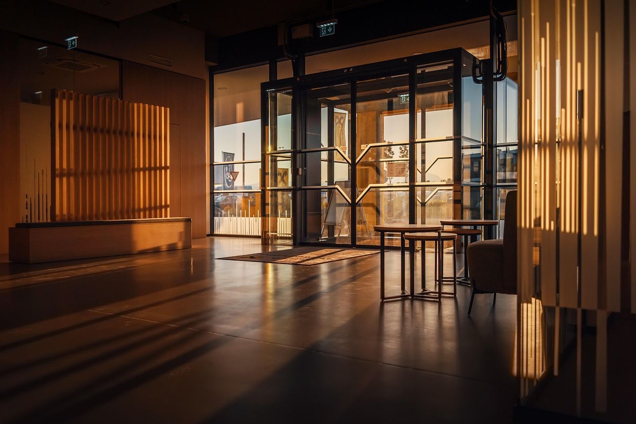 Recepção do prédio ao entardecer, com a porta de vidro ao fundo