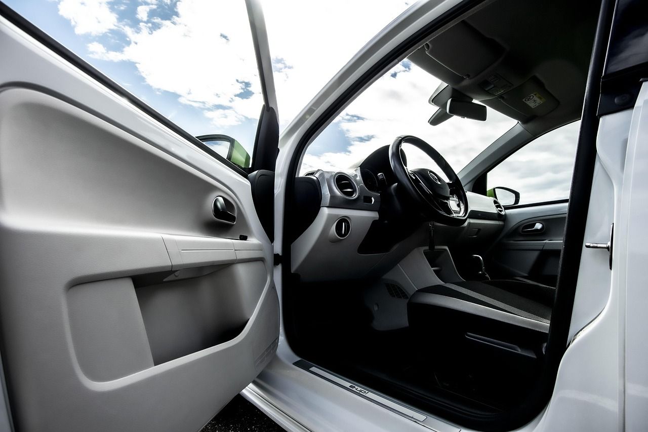 Interior de um carro visto pela porta aberta, com o volante e o painel