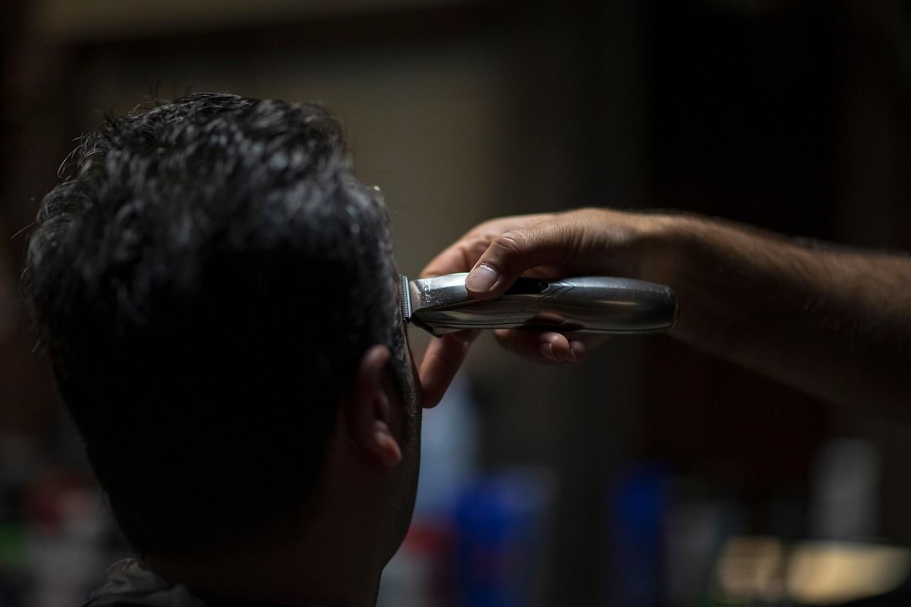 Máquina de corte fazendo o acabamento na lateral do cabelo de um cliente