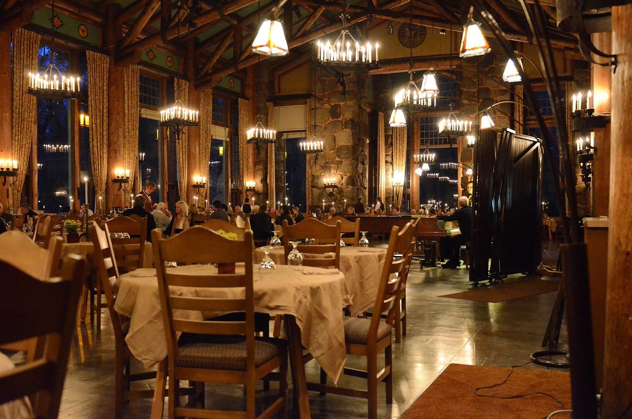 Salão da Cantina Araucária, em madeira e pedra, com lustres de velas e mesas postas