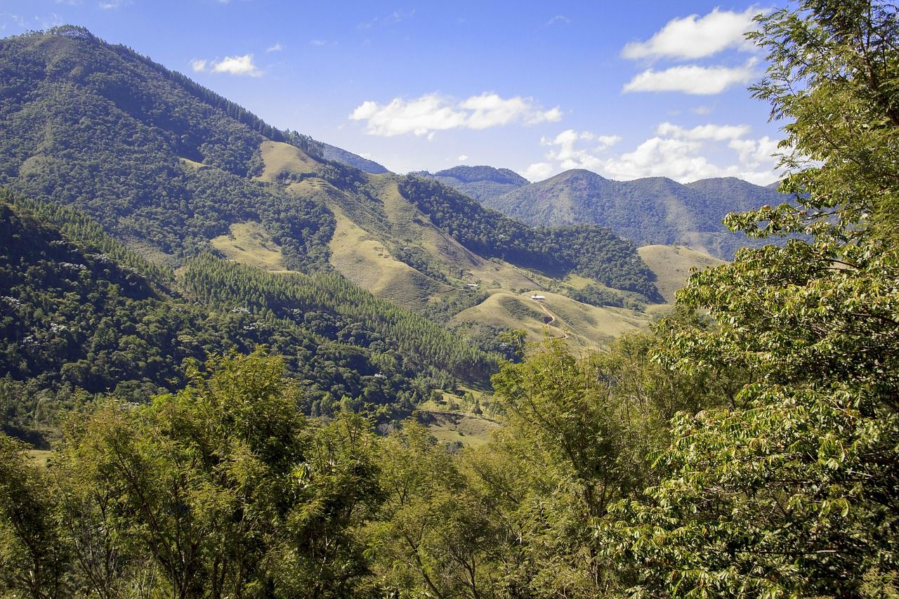 Serra coberta de mata e pastos, vista do alto num dia de sol